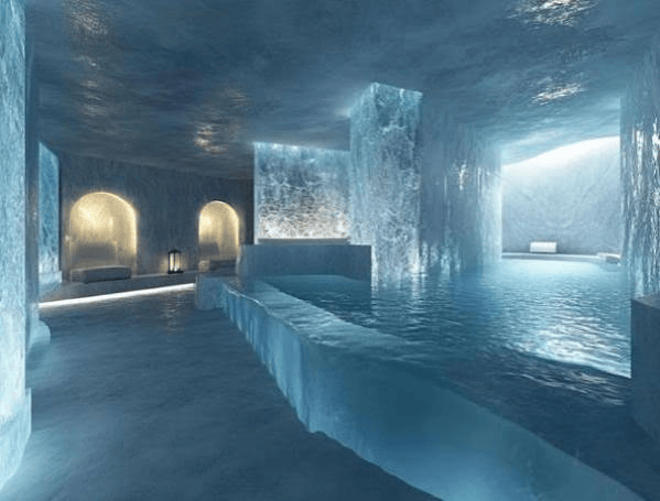 Interior de un spa de hielo con paredes de hielo, iluminación suave y una piscina de agua clara.