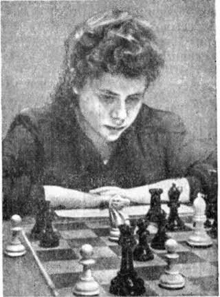 Una mujer concentrada jugando al ajedrez, observando el tablero con piezas blancas y negras.