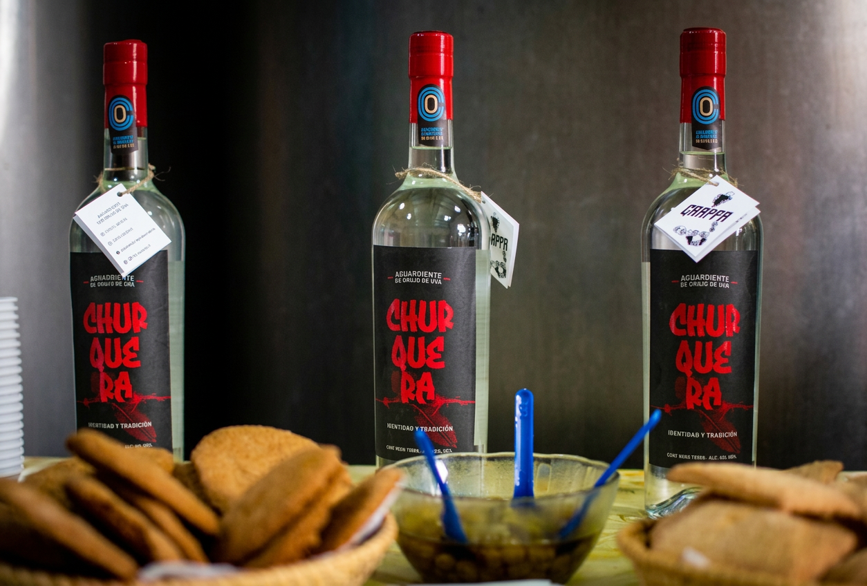 image Botellas de aguamiel Churra acompañadas de galletas y un recipiente con salsa.