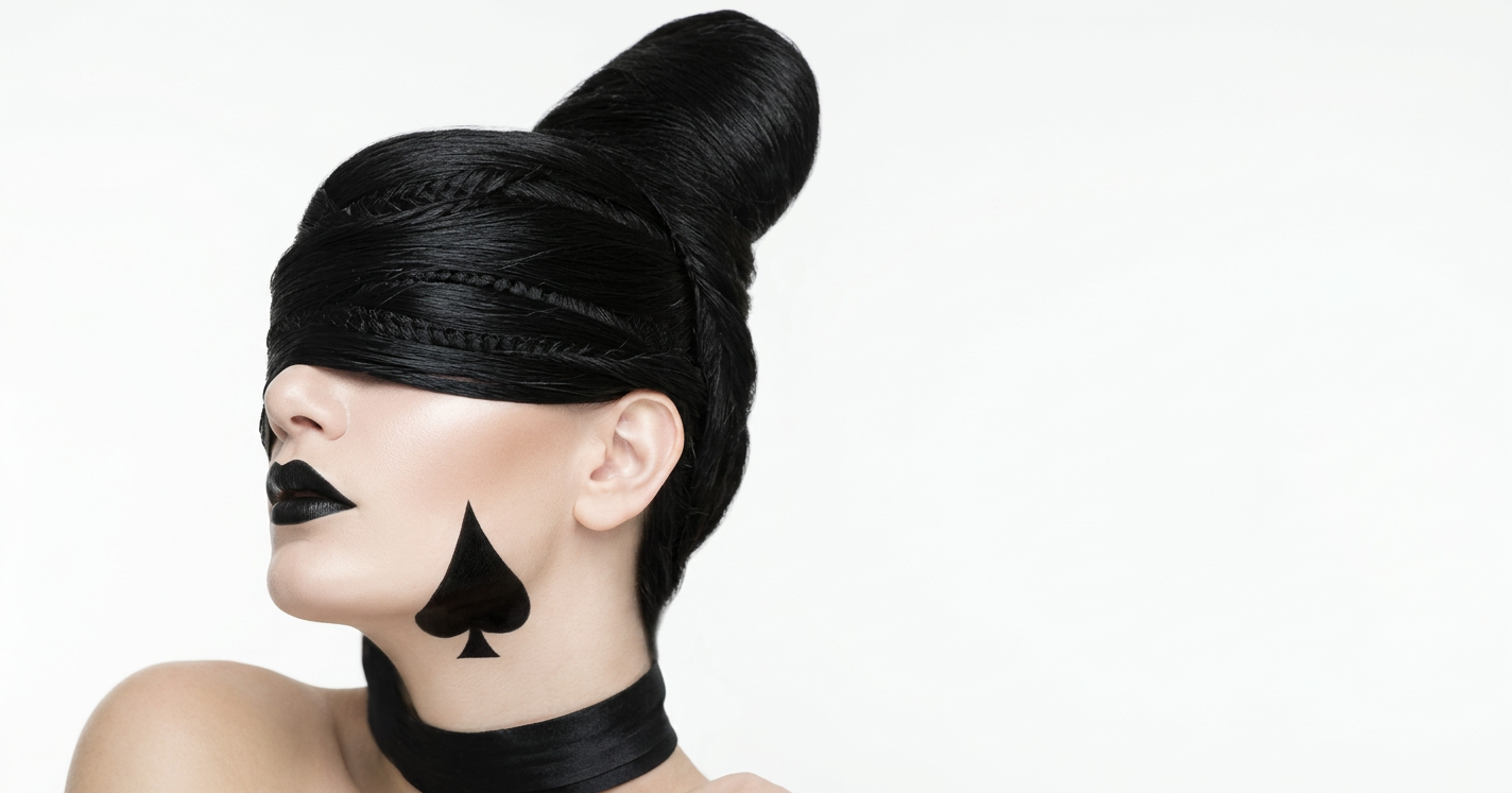 PicasD Retrato de una mujer con el cabello negro revestido y vendado sobre los ojos, mostrando un diseño de trébol negro pintado en su mejilla y labios pintados de negro.
