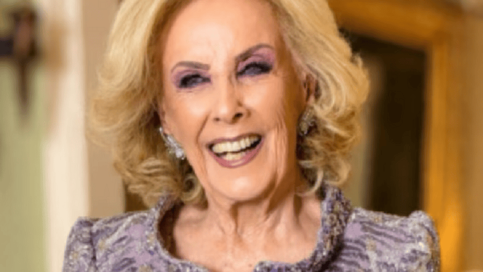 Mujer de cabello rubio y rizado, sonriendo mientras viste un elegante vestido púrpura.