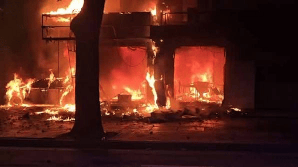 Edificio en llamas con fuego intenso y humo, mostrando daños significativos.