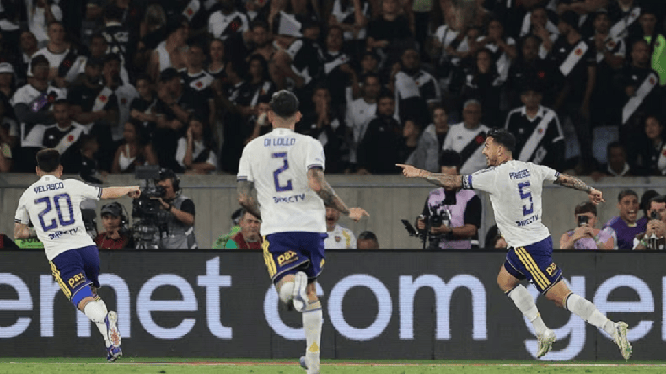 Jugadores de fútbol celebrando un gol en un estadio lleno de aficionados.