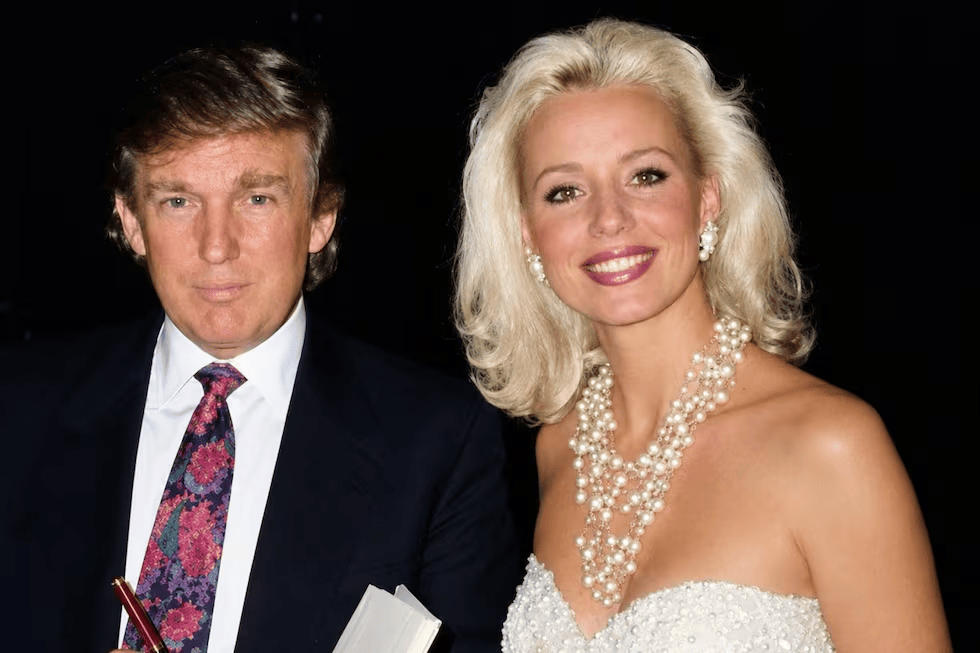 Hombre y mujer posando juntos, el hombre lleva una chaqueta oscura y corbata, la mujer usa un vestido elegante y un collar de perlas, ambos sonríen.