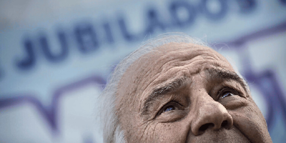 Primer plano de un hombre mayor mirando hacia arriba, con expresión reflexiva, y un fondo difuso con el texto 'Jubilados'.