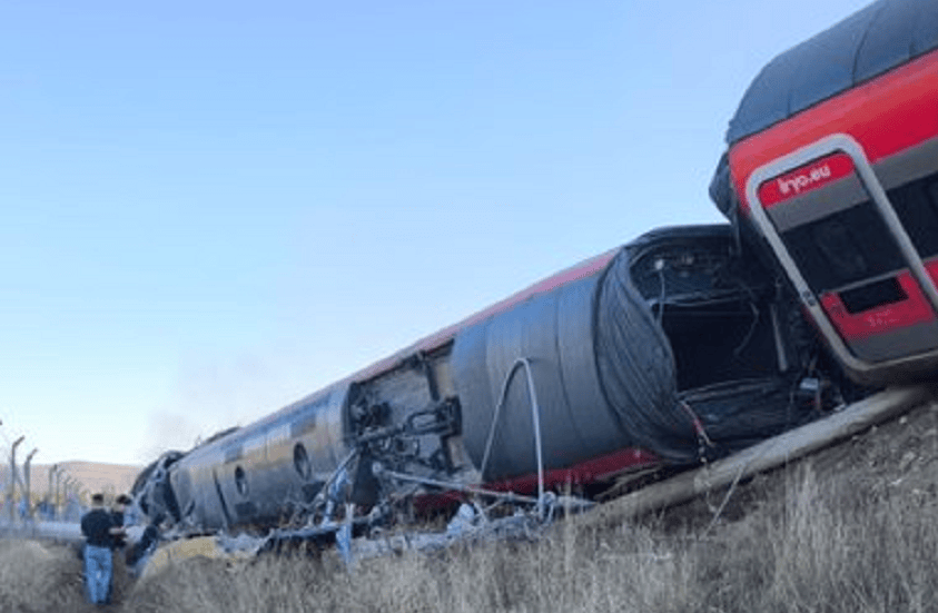 Un tren descarrilado en un paisaje abierto, con un hombre de pie observando los daños.
