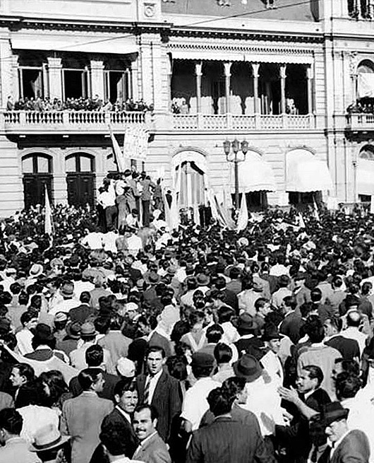 Multitud de personas reunidas en una plaza, frente a un edificio histórico, durante un evento o manifestación.